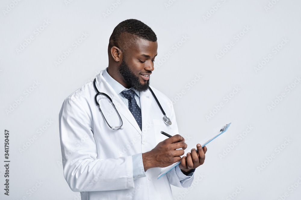 Smiling black doctor with stethoscope collecting patient anamnesis Smiling black doctor with stethoscope collecting patient anamnesis