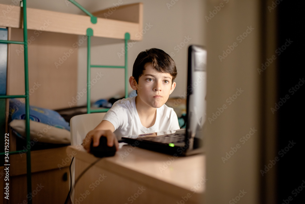 A boy using a laptop in his workspace A boy using a laptop in his workspace