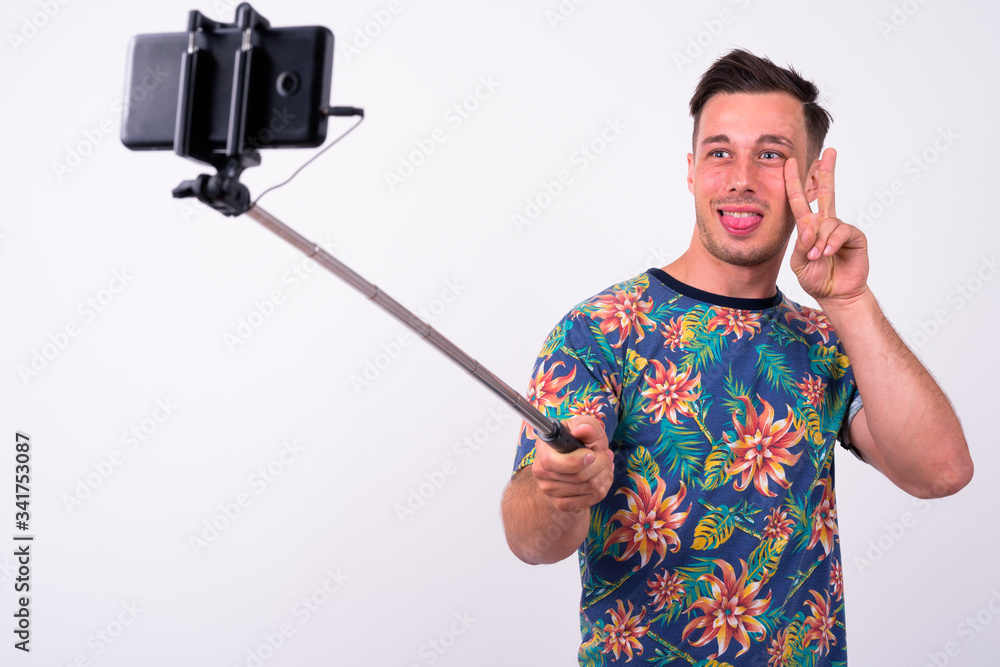Portrait of happy young tourist man taking selfie with phone on selfie stick Portrait of happy young tourist man taking selfie with phone on selfie stick