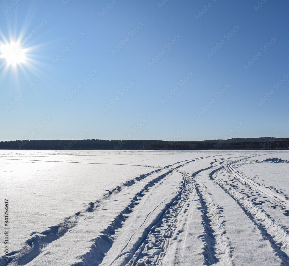 Most beautiful winter landscape. Snowy road. Bright sun over the winter lake. Place for text. Most beautiful winter landscape. Snowy road. Bright sun over the winter lake. Place for text.