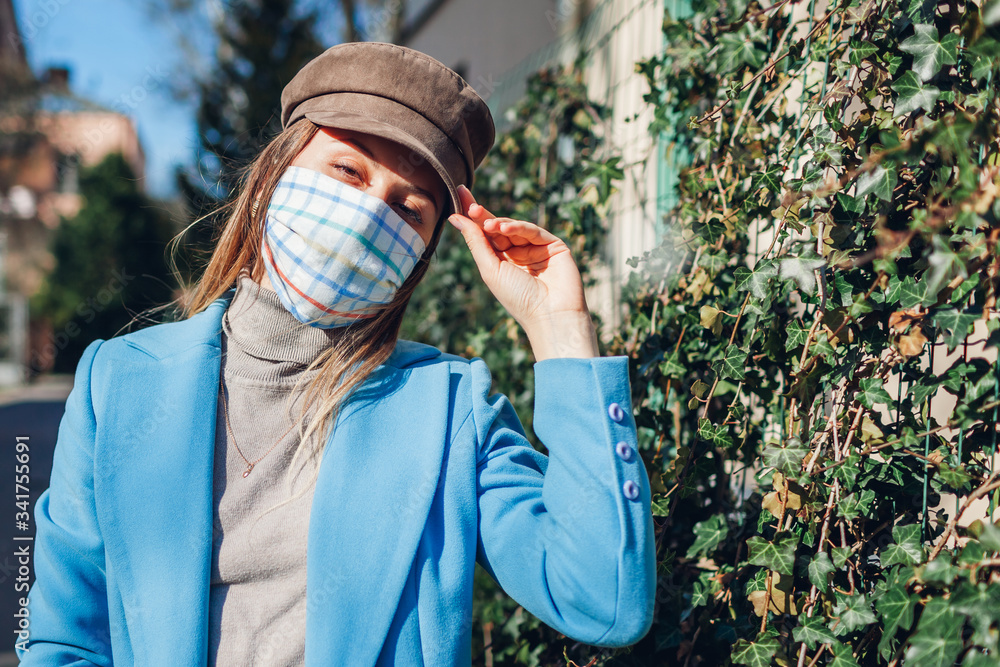Woman wears reusable handmade protective mask outdoors during coronavirus covid-19 pandemic on empty street.