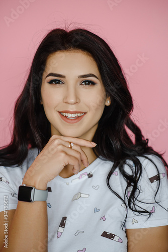 Close-up Portrait of a beautiful young girl, isolated on pink background. Studio shot. Photography of a Young smiling cute brunette in a white t-shirt on a pink background