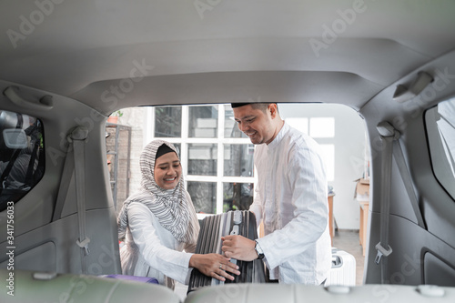 muslim couple packing suitcase in the car trunk for holiday