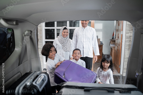 muslim family load their suitcase in to car trunk. preparing for eid mubarak holiday