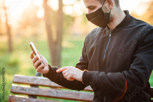 Man in mask drives his finger on the phone. Coronavirus. Cough. Security. Man. Phone in the hands of man. The masked man plays the phone.