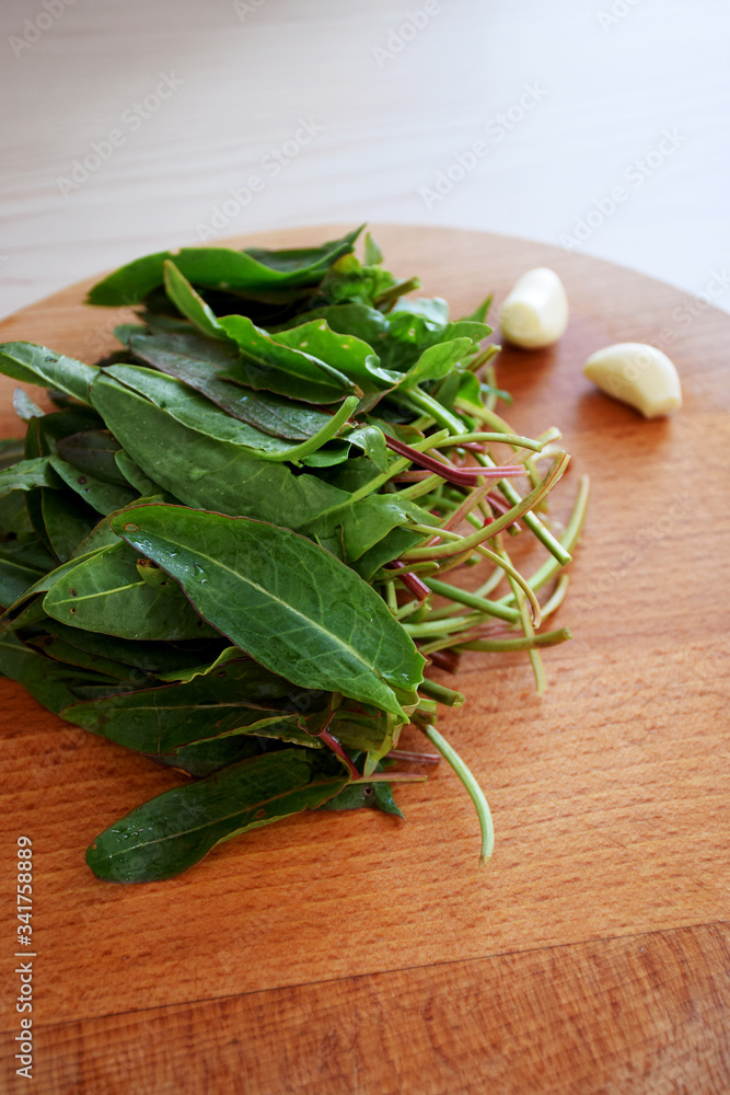Sorrel, spinach and garlic on wooden cutting board Sorrel, spinach and garlic on wooden cutting board
