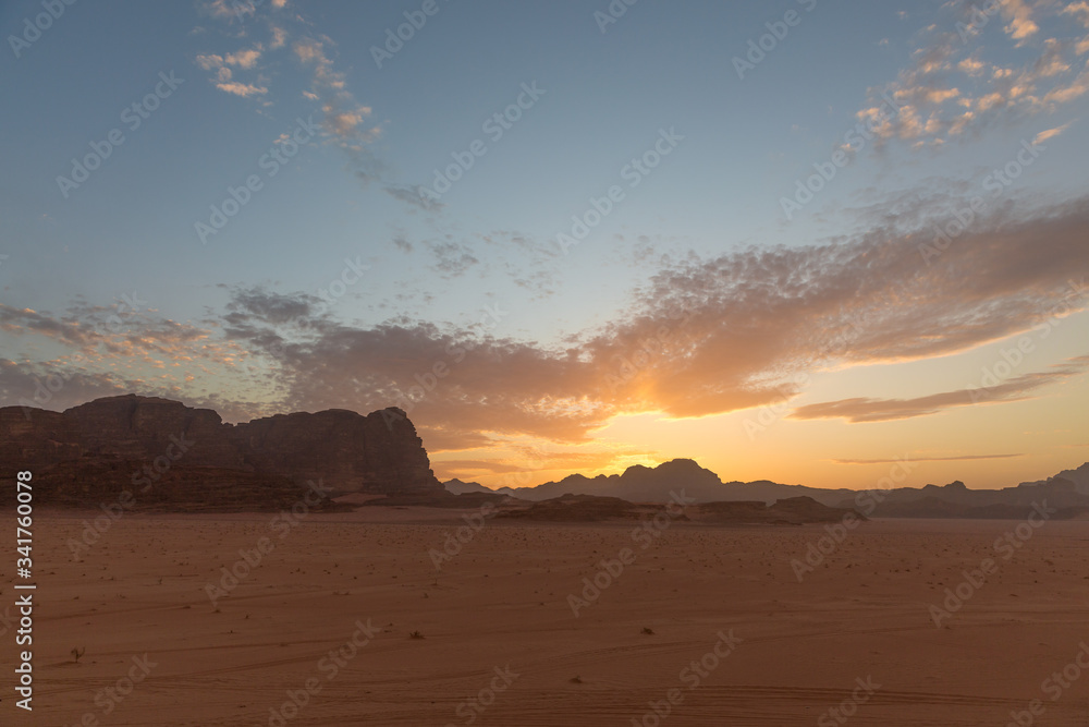 Incredible sunset in the Wadi Rum desert. The blue sky is covered with cirrus clouds. View from the cliff