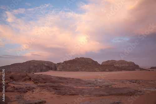 Purple sunset in the Wadi Rum desert. The blue sky is covered with pink clouds. View from the cliff