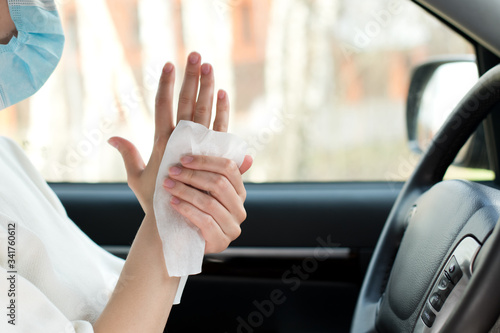 female hands are treated with an antiseptic wipe in a car
