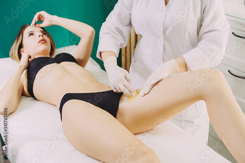 Bikini depilation waxing. The master makes hair removal in the salon