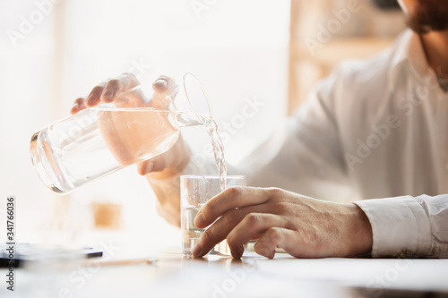 Puring water. Close up of caucasian male hands, working in office. Concept of business, finance, job, online shopping or sales. Copyspace for advertising. Education, communication freelance.