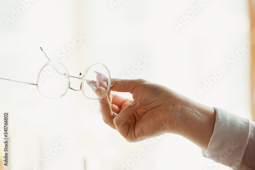 Holding eyeglasses. Close up of caucasian female hands, working in office. Concept of business, finance, job, online shopping or sales. Copyspace for advertising. Education, communication freelance.