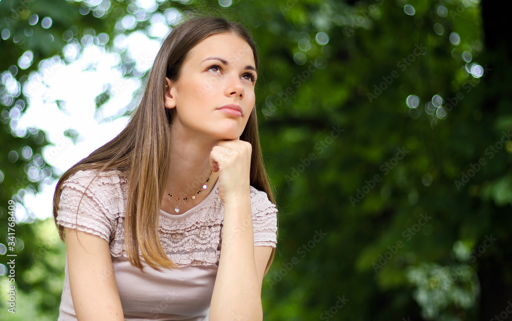 portrait of a pretty thoughtful lady sitting on a banch in a park portrait of a pretty thoughtful lady sitting on a banch in a park