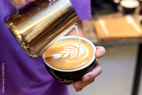 The Barista makes a drawing on a coffee latte or cappuccino