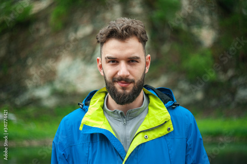 Portrait of a young, bearded man, on, against a background of wildlife. The concept of expedition, adventure and camping life.