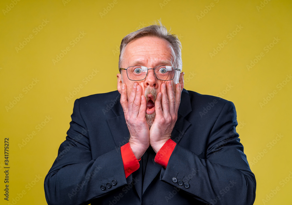 Scared frightened senior man. Frightaned of something. Man covers widely opened mouth with both hands. Displeased surprised expression. Man dressed in suit. Negative emotions. Scared frightened senior man. Frightaned of something. Man covers widely opened mouth with both hands. Displeased surprised expression. Man dressed in suit. Negative emotions.