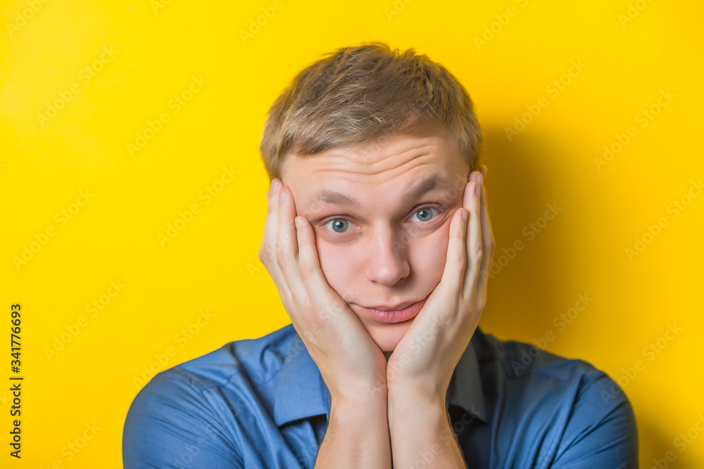 Blond young man. Gesture. Sadness. does not know what to do, confusion. Isolated yellow background. Blond young man. Gesture. Sadness. does not know what to do, confusion. Isolated yellow background.