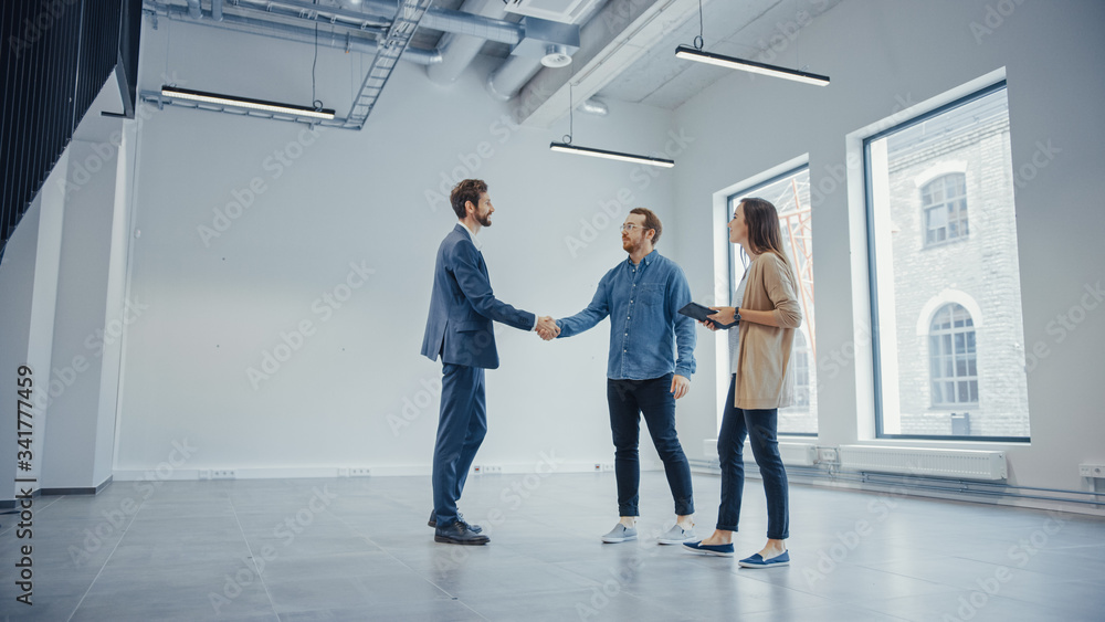 Real Estate Agent Showing a New Empty Office Space to Young Male and Female Hipsters. Entrepreneurs Meet the Broker and They Hand Shake. They Wish to Purchase or Rent.