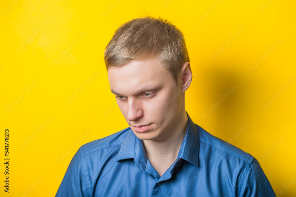 Young man close-up in a blue shirt on a yellow background, thoughtful, sad. Mimicry. Gesture. photo Shoot Young man close-up in a blue shirt on a yellow background, thoughtful, sad. Mimicry. Gesture. photo Shoot