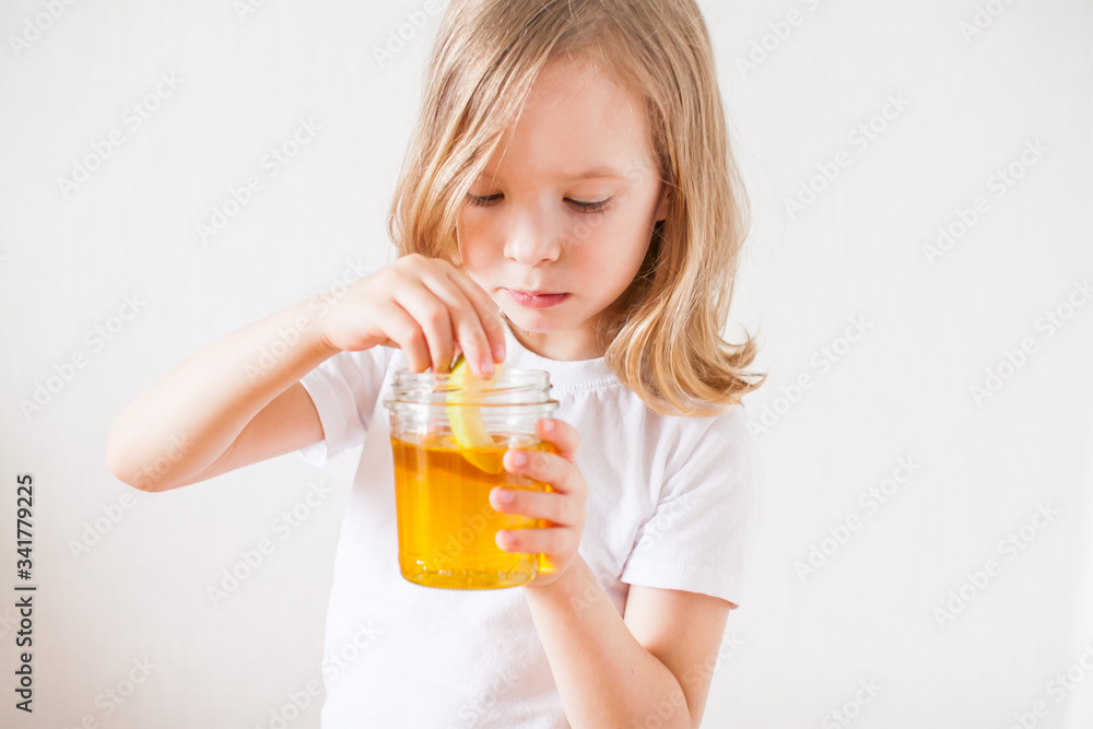 A little girl holds a jar of honey and a slice of apple in her hands. Symbols and traditions of the Jewish New Year. Rosh ha Shana A little girl holds a jar of honey and a slice of apple in her hands. Symbols and traditions of the Jewish New Year. Rosh ha Shana