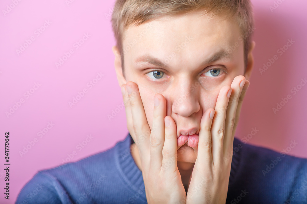 The young man looks sadly. Gesture. On a purple background. The young man looks sadly. Gesture. On a purple background.