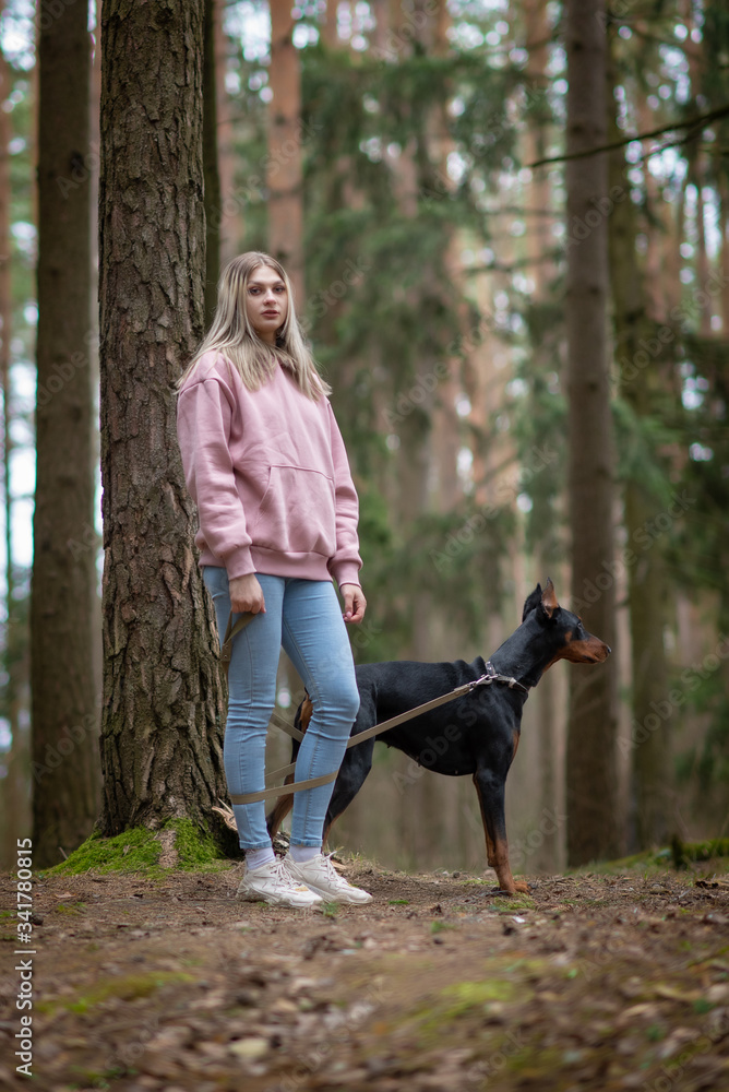 Portrait of a blonde with a doberman in the forest. Portrait of a blonde with a doberman in the forest.