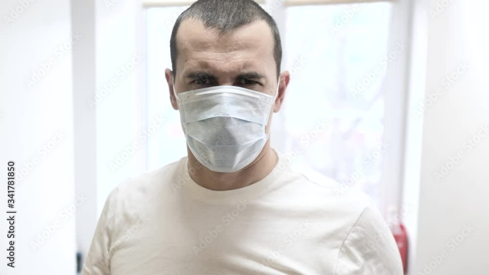 man in a medical mask shows a gesture stop infection disease. concept pandemic virus self-isolation covid 19 infection doomsday. man a indoors home isolation lifestyle portrait man in a medical mask shows a gesture stop infection disease. concept pandemic virus self-isolation covid 19 infection doomsday. man a indoors home isolation lifestyle portrait