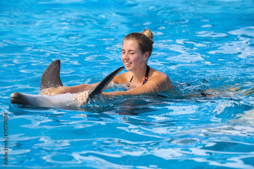 happy young woman swimming with dolphin
