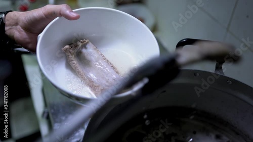 Close up scene of serving Bak Kut Teh with the pork ribs into the bowl, food processing, Malaysian and Singaporean traditional dish, cooking step, food preparation, the famous dish. photo