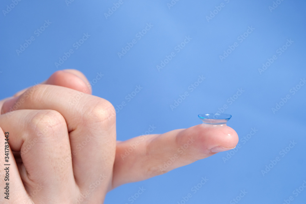 Contact lenses on the fingertip on a blue background, space for text Contact lenses on the fingertip on a blue background, space for text