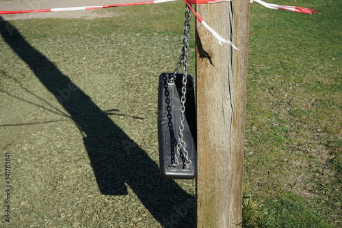 Mit Absperrband festgebundene Schaukel in einem Park in Berlin während der Coronakrise photo