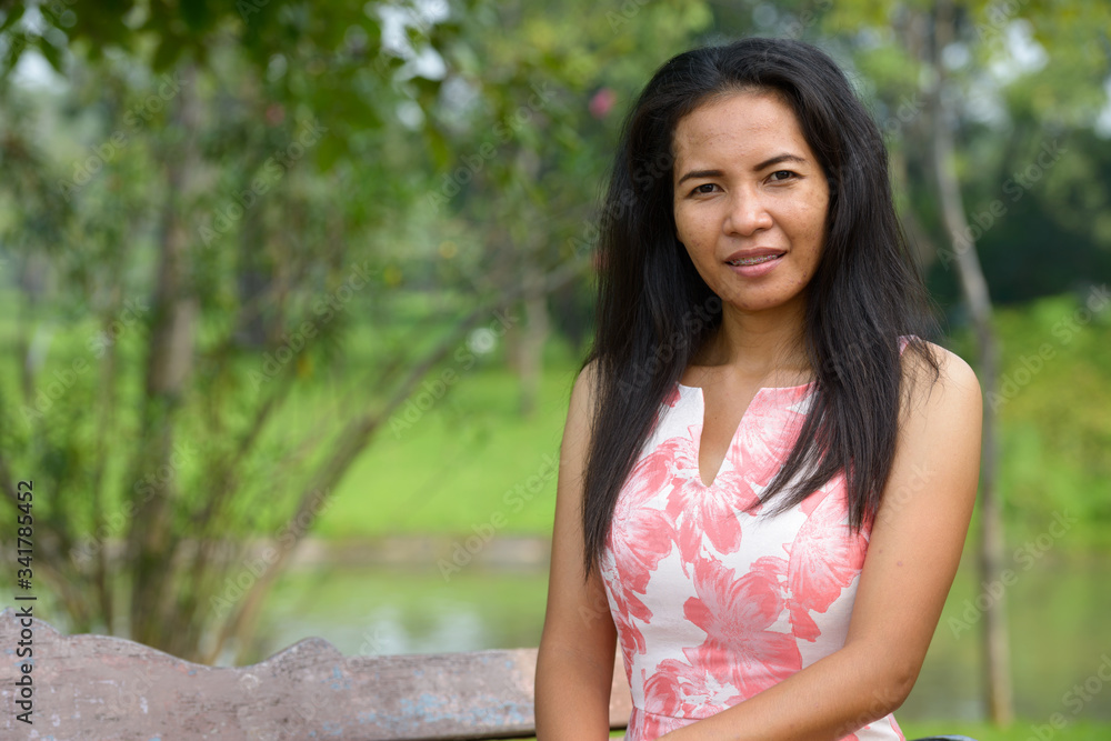 Happy mature Asian woman relaxing at the park outdoors Happy mature Asian woman relaxing at the park outdoors