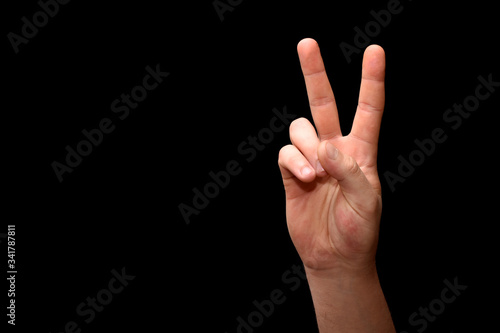 victory symbol formed from fingers on a black background.