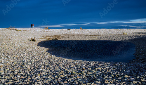 stony pebble beach with people watching out to sea photo