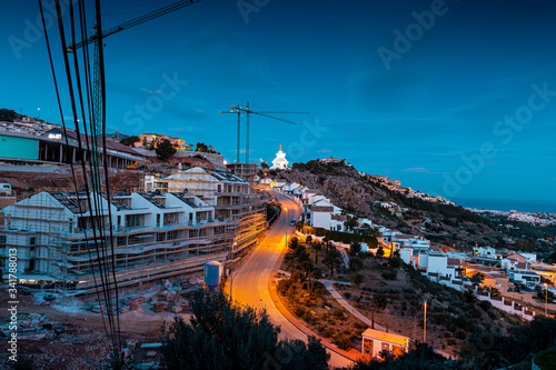 New residential building and a Buddhist white monument with a golden peak at night.  Benalmadena, Malaga / Spain