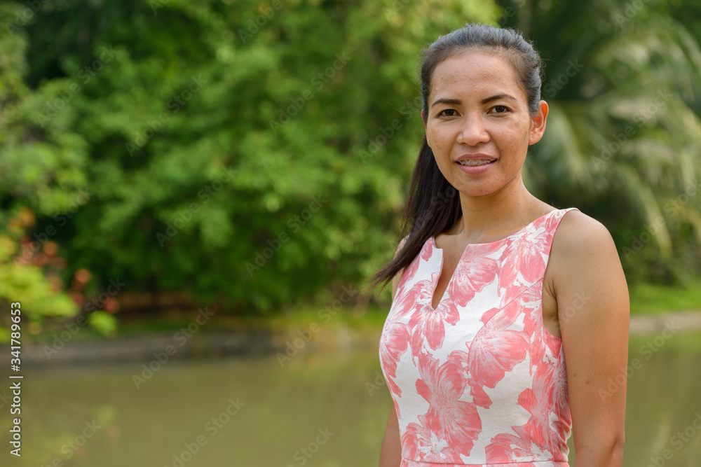 Happy mature Asian woman relaxing at the park outdoors Happy mature Asian woman relaxing at the park outdoors