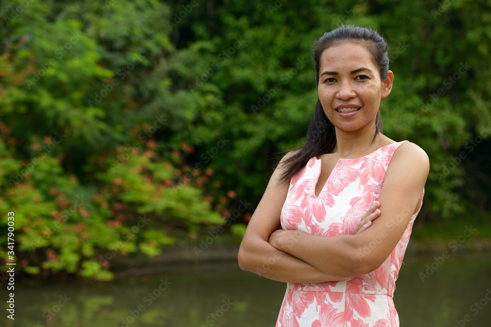 Happy mature Asian woman relaxing at the park outdoors Happy mature Asian woman relaxing at the park outdoors