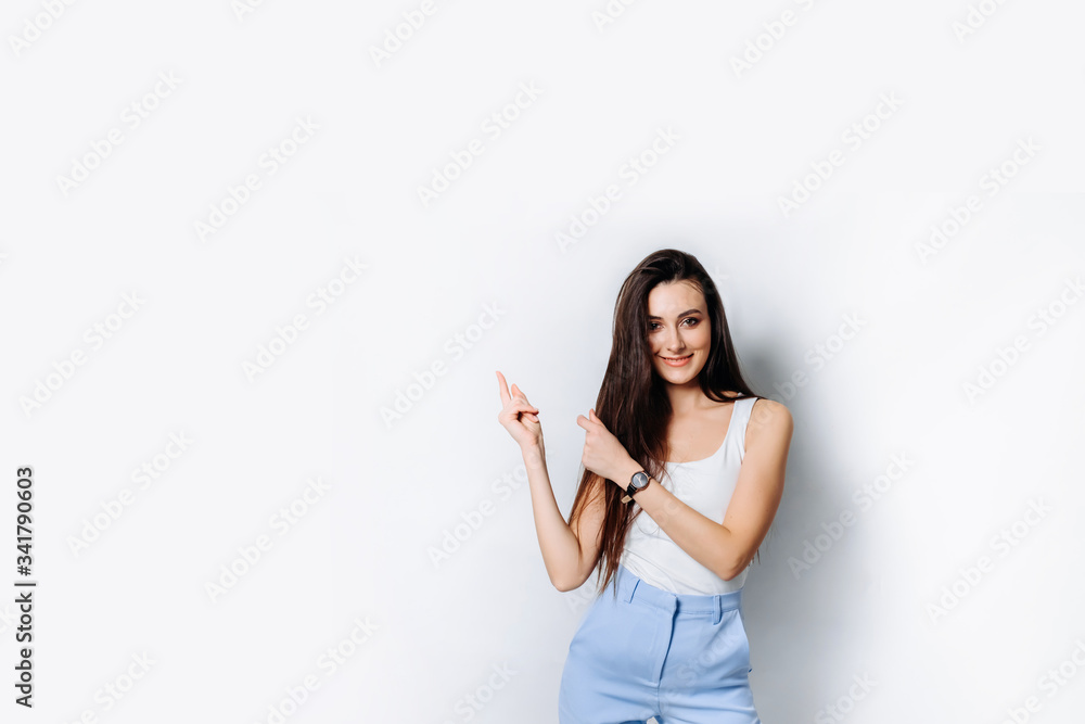 Portrait with a copy of the space of a charming brunette pointing her index finger at an empty space Portrait with a copy of the space of a charming brunette pointing her index finger at an empty space