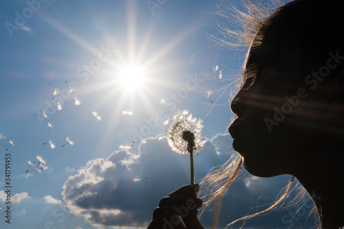 Obraz na plátně girl blowing dandelion against the light