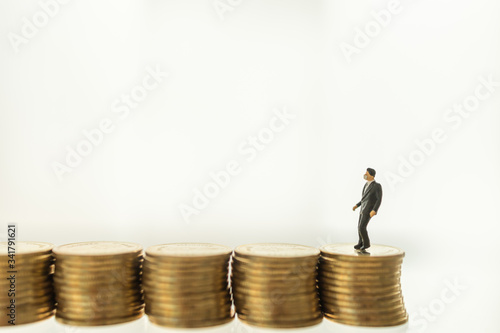 Healthcare,  Coronavirus (COVID-19) situation Business and Econony Cocept. Businessman miniature figure people with face mask standing and walking on stack of coins with copy space.
