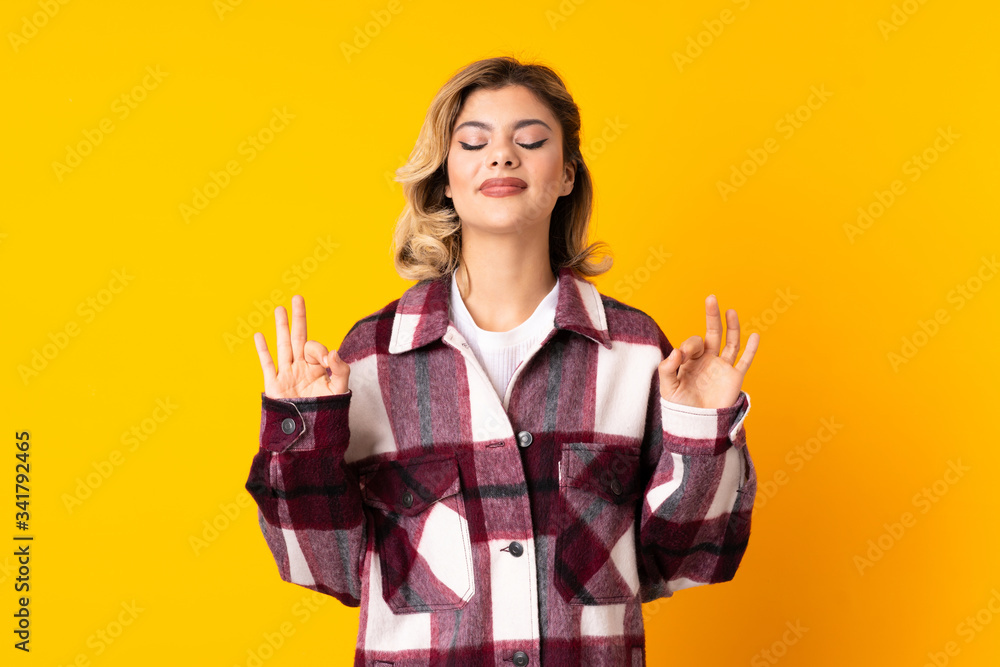 Young Russian woman isolated on yellow background in zen pose