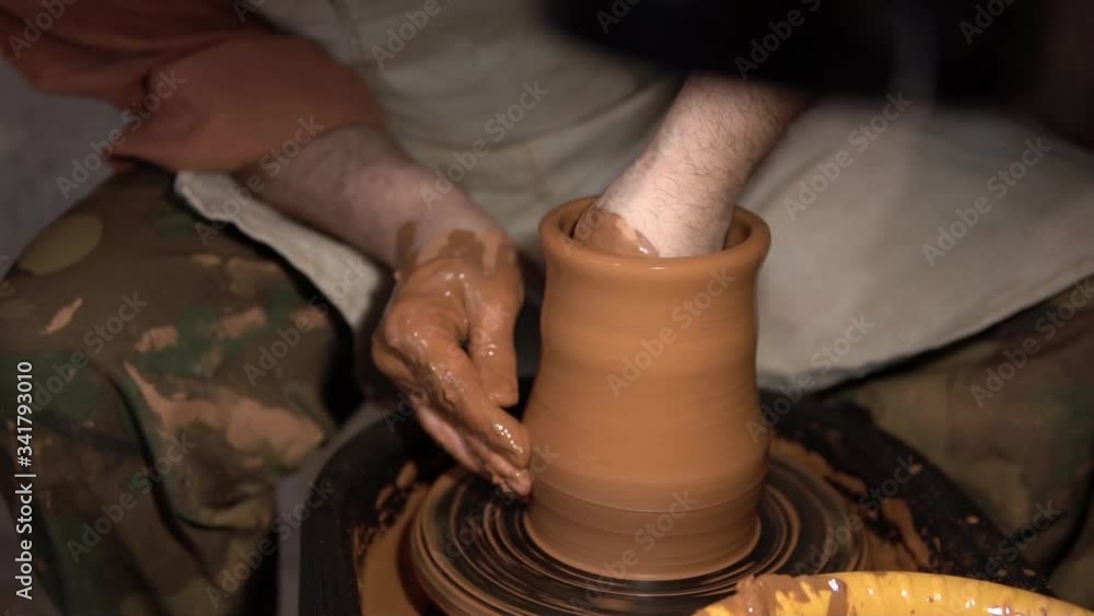 pottery making. potter's hands shaping up the terracotta clay pot on wheal.