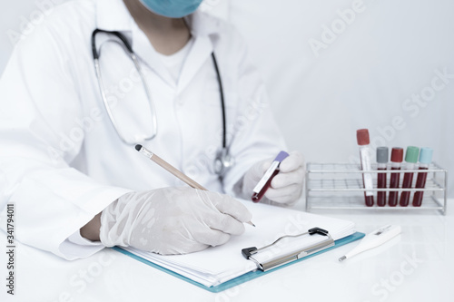 Doctor hand holding blood tube and recording the results of the blood test