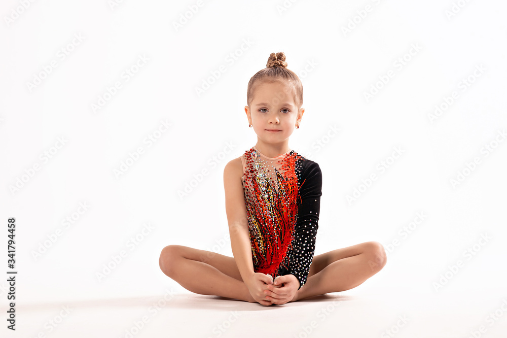Rhythmic gymnastics. Girl gymnast sitting on a white background. Children and sports, healthy lifestyle. Rhythmic gymnastics. Girl gymnast sitting on a white background. Children and sports, healthy lifestyle.