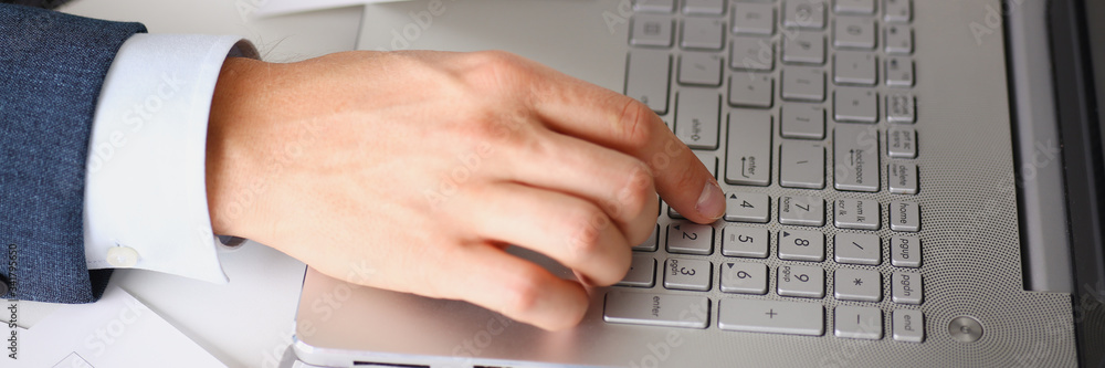 Male hands hold documents laptop with financial statistics at office workspace closeup. White collar check money papers, stock exchange market, internal Revenue Service inspector, earning list concept Male hands hold documents laptop with financial statistics at office workspace closeup. White collar check money papers, stock exchange market, internal Revenue Service inspector, earning list concept