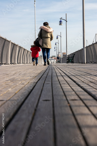 A mother and son walking together along an old wooden pier