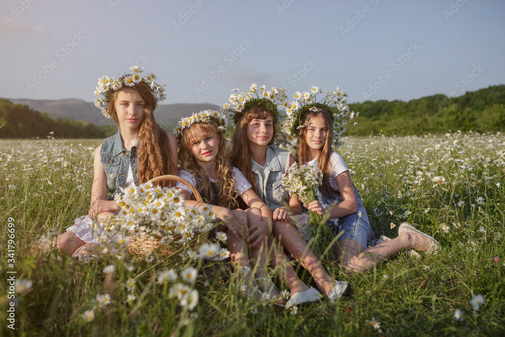 Fototapeta premium Four Teen girls enjoys spring in daisy field.