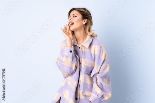 Young Russian woman isolated on blue background shouting with mouth wide open to the side