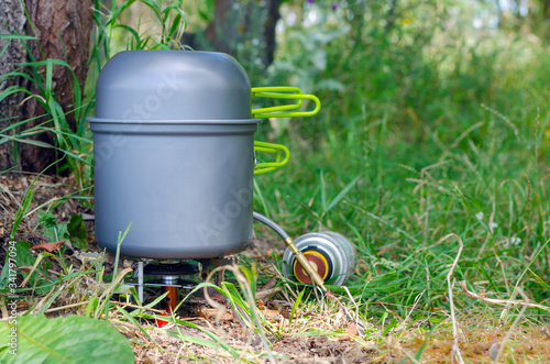 Gas burner with a bowler hat on the green grass  cooking in the hike