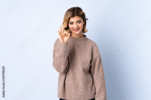 Young Russian woman isolated on blue background showing ok sign with fingers